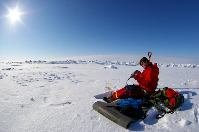 A man sitting in the snow with a backpack.