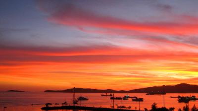 A sunset over a harbor with boats in it.