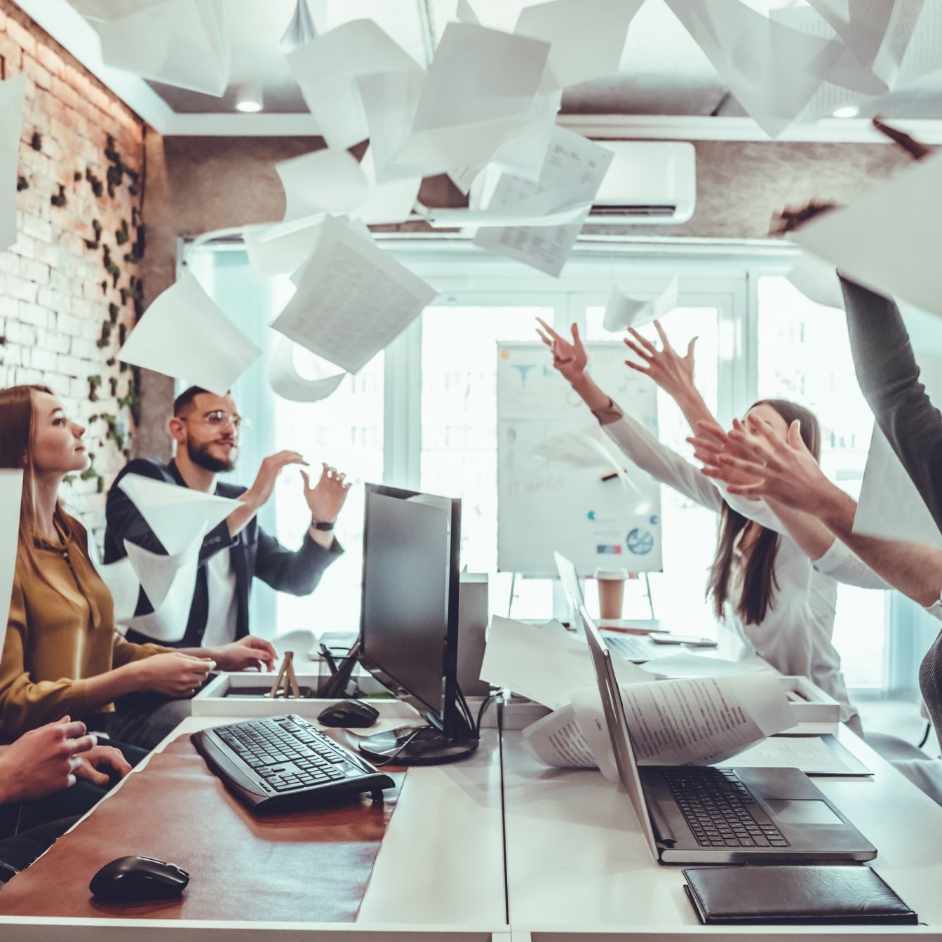 Article thumbnail: Smiling business people having fun by throwing papers in the air celebrating business success in the modern office. Happy workplace and casual career company concept.