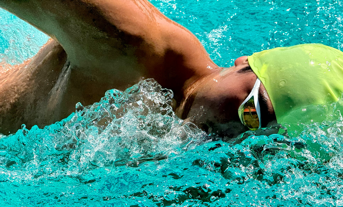 一张细节鲜明的变焦放大照片，画面中一个人在泳池游泳，身边水花四溅