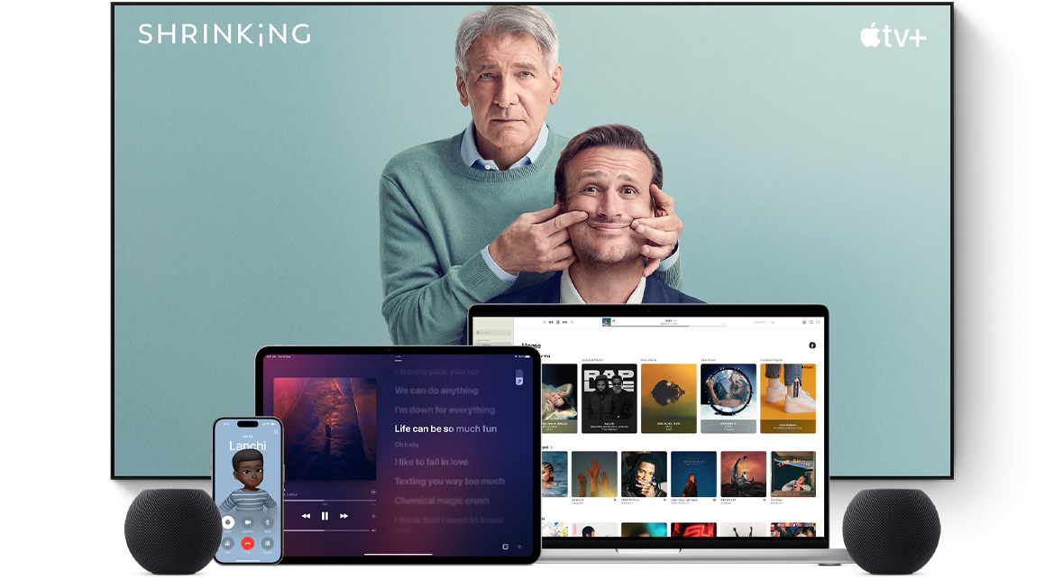 Large flat screen television showing two male characters from the Apple TV+ series shrinking. A MacBook Pro, an iPad, an iPhone and a Space Grey HomePod mini are arranged in front.