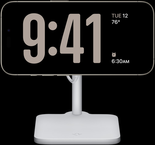 iPhone 15 Pro v pohotovostnom režime zobrazujúci hodiny na celú obrazovku, dátum, teplotu a najbližší budík