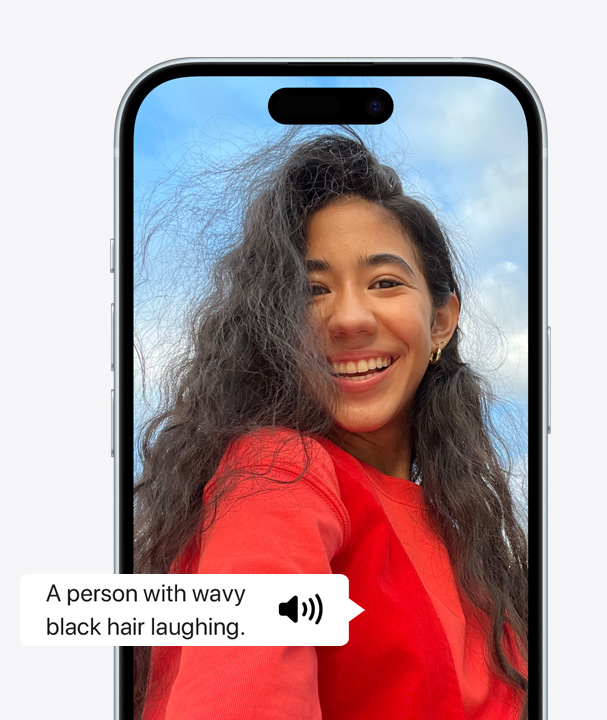 A picture of an iPhone using VoiceOver to describe the details of a person with wavy hair on screen laughing.