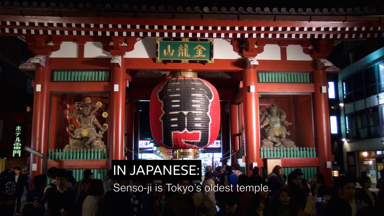 Screen shot of Japanese temple with subtitle IN JAPANESE: above burnt-in translation