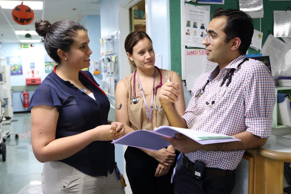 Three doctors in discussion on ward.