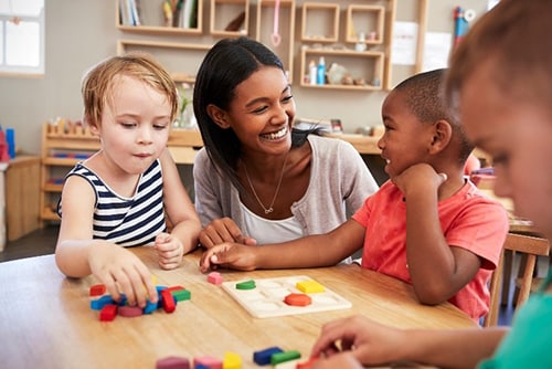 Smiling female teacher working with three young children