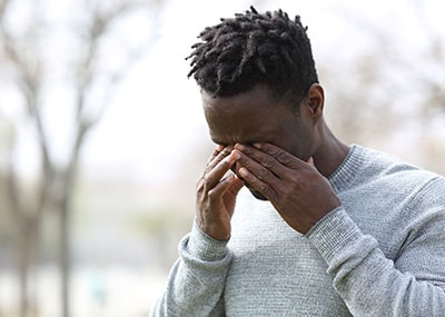 Man stands outside rubbing his eyes