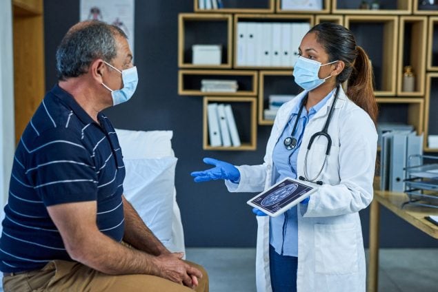 Doctor holds a tablet with brain images in her hand and explains findings to a patient.