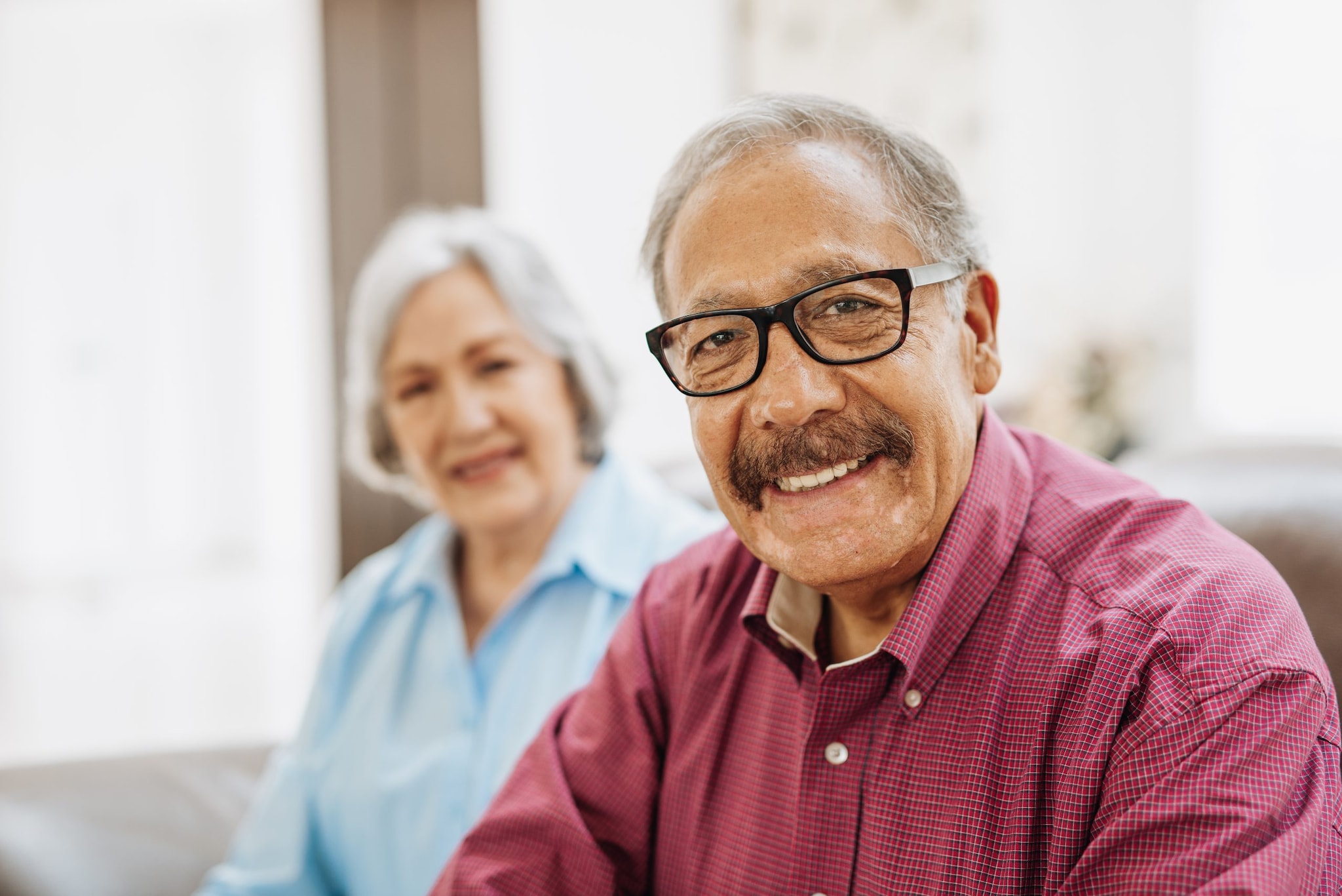 Older couple smiling on couch.