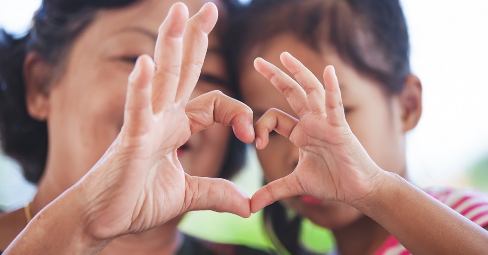 Mother and daughter forms heart shape from their fingers