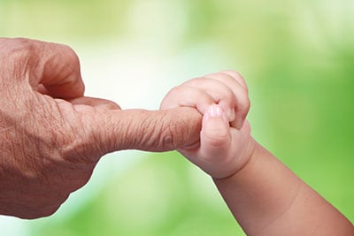 Bebé agarrando el dedo índice de un adulto.