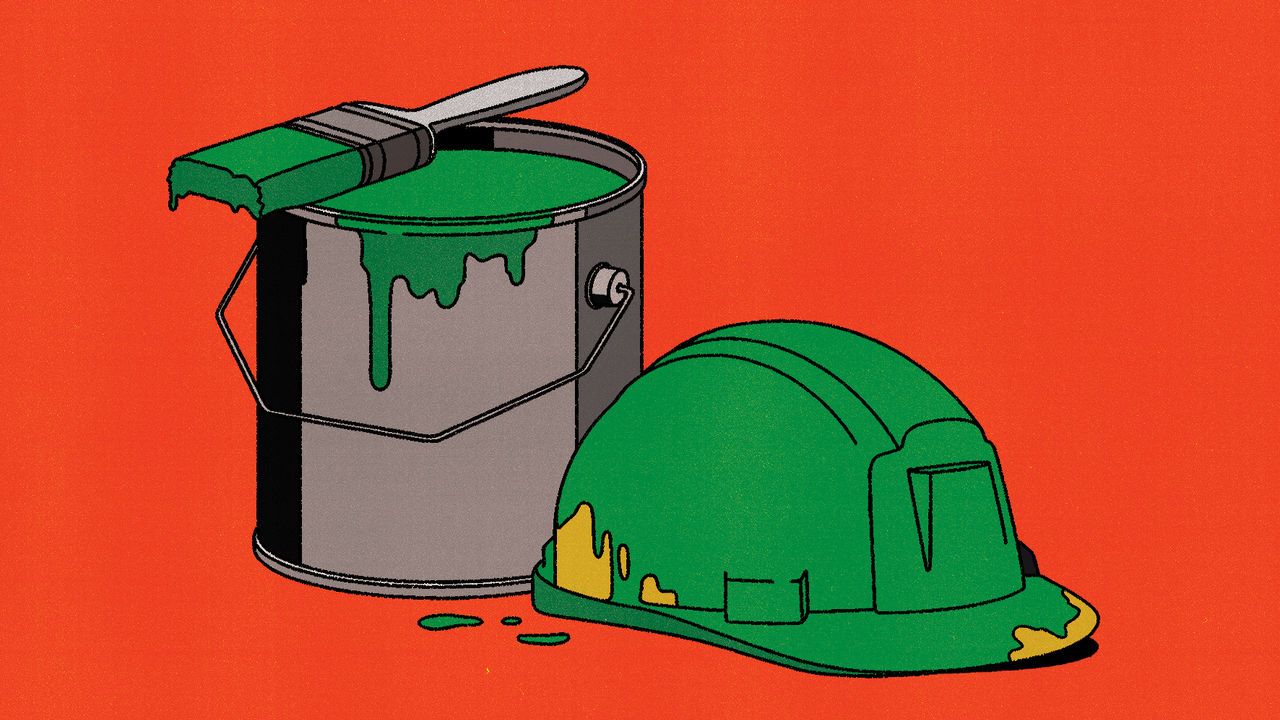 A safety helmet roughly painted in green, positioned beside a bucket of green paint.