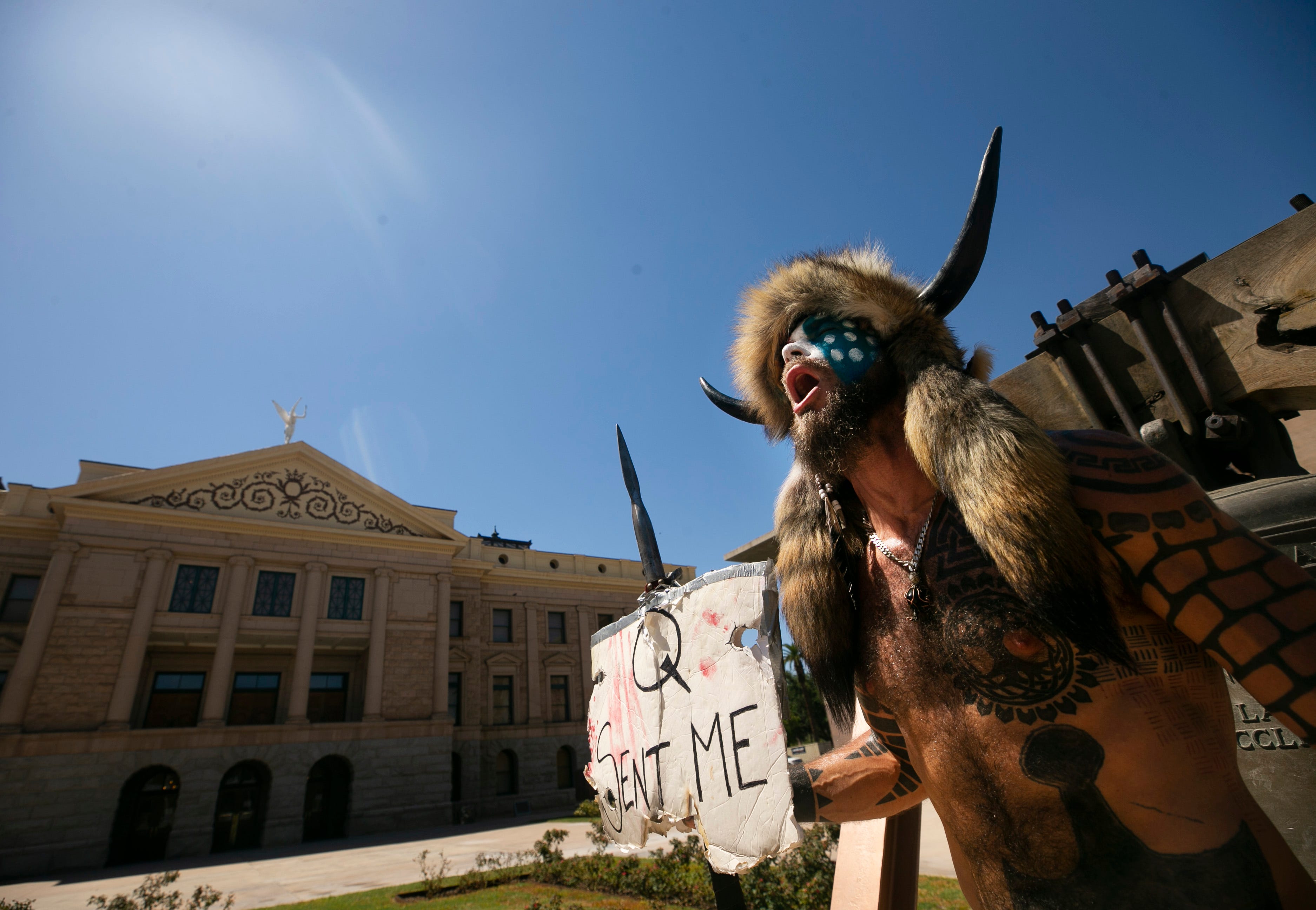 Jake Angeli, who supports QAnon, shouts about reopening schools in the midst of the COVID-19 pandemic at the state Capitol on Aug. 12, 2020.