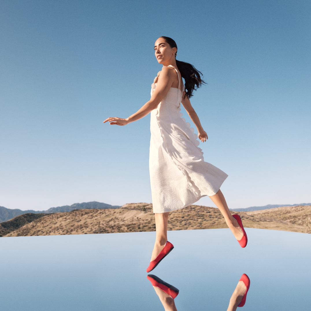 A model wearing Rothy's shoes over a mirror in the desert.