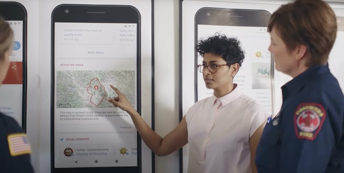 Three people looking at a map of wildfire affected area on a wall