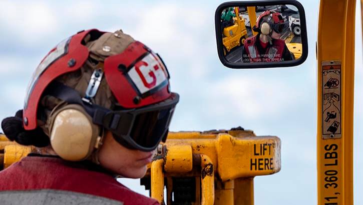 Aviation Ordnanceman 3rd Class Dominique Campbell drives a forklift on the flight deck of the Nimitz-class aircraft carrier USS Harry S. Truman (CVN 75) during a vertical replenishment. She is wearing proper hearing and vision protection.