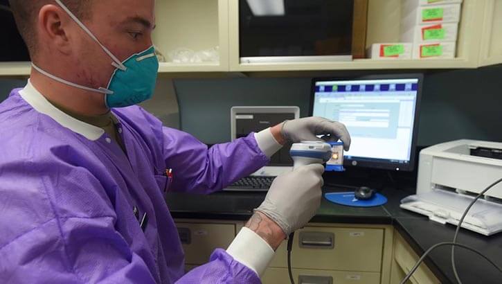 Military personnel preparing a COVID-19 test sample for processing