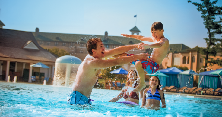 Father throwing son in Hotel Hershey pool while mother and daughter watch in the background.