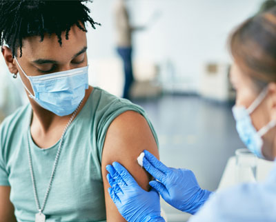 Person preparing a patient’s arm to administer a vaccine.