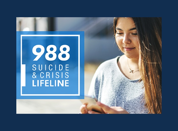 988 Suicide & Crisis Lifeline; Young woman with long hair looking at her mobile device.