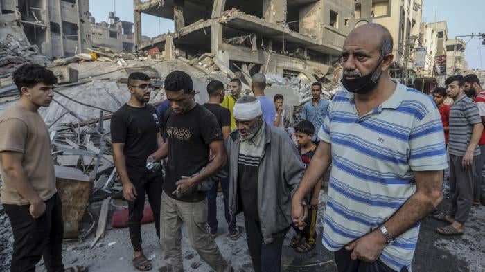 Palestinians help an injured older man following overnight Israeli air strikes on the Rafah refugee camp in Gaza, October 25, 2023.