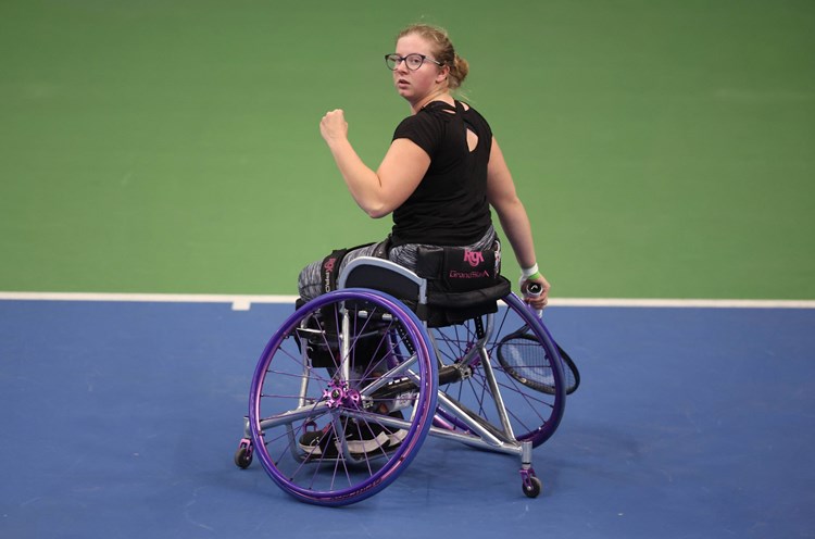 Abbie Breakwell clenching her fist on court while sat in her wheelchair and holding her tennis racket