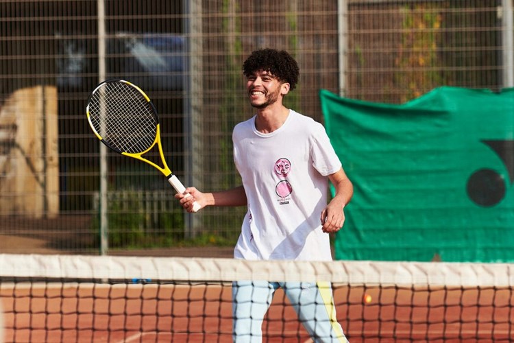 Young male player having fun on a clay tennis court