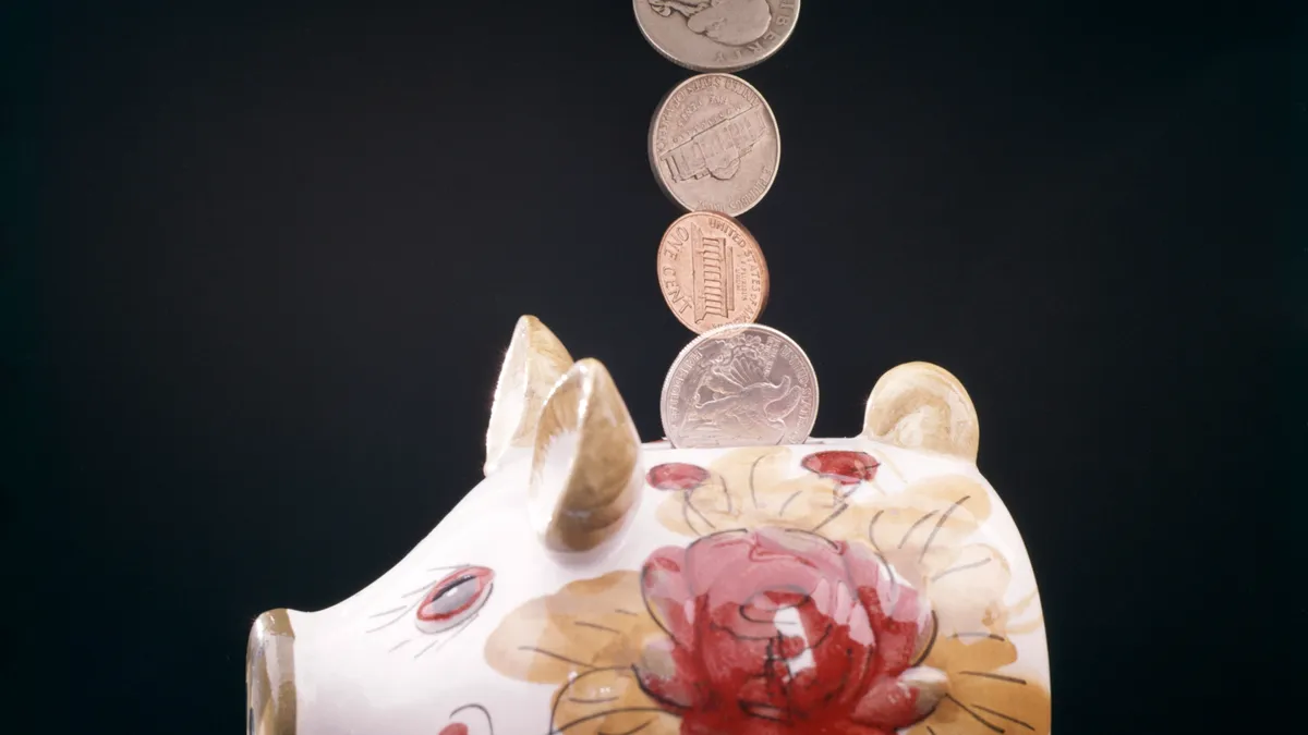 Faucet pouring coins into piggy bank