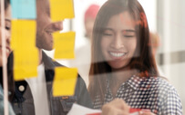 man and two women working together and putting sticky notes on a pane of glass