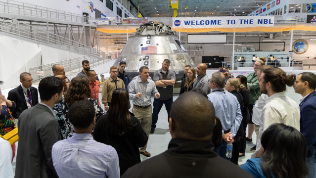 A group of people listen to a man speaking