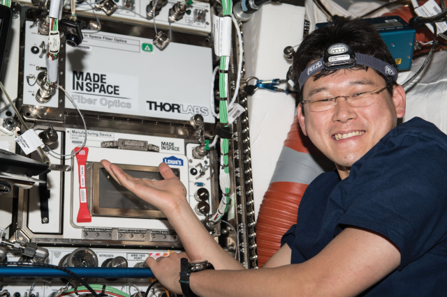 image of an astronaut posing next to 3D printer aboard the space station