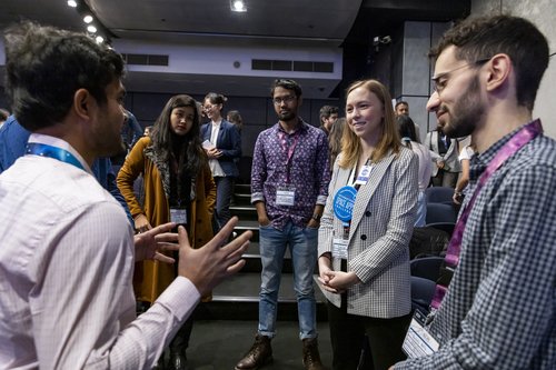 A small group of people listen intently to a man talking