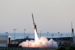 A sounding rocket seconds in mid-launch off the launch pad with a bright white plume underneath.