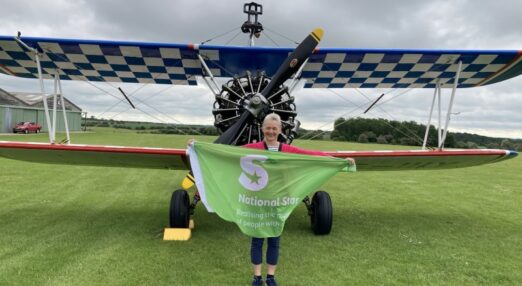 Female supporter holding National Star flag in front of plane