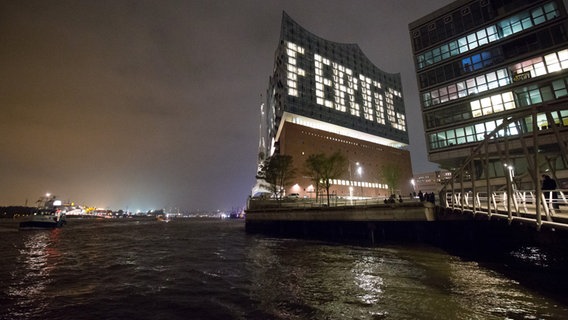 Durch unterschiedlich beleuchtete Fenster ist auf einer Fassade der Elbphilharmonie  in Hamburg das Wort "Fertig" zu lesen. © dpa-Bildfunk Foto: Christian Charisius