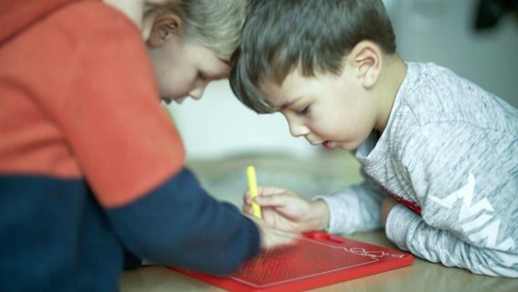 Drei Kinder sitzen auf dem Boden und malen. © NDR 