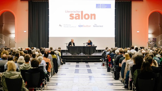 Robert Seethaler und Joachim Dicks sitzen vor Publikum auf einer Bühne im Lichtsaal des Welfenschlosses. © Nerea Lakuntza Foto: Nerea Lakuntza