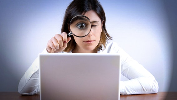 Eine Frau blickt mit einer Lupe auf einen Laptop. © iStock, Fotolia Foto: muharrem öner, Matthias Enter