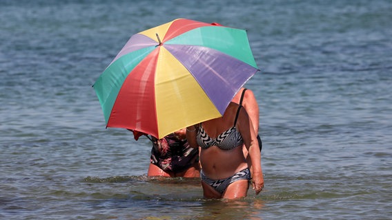 Zwei Frauen stehen mit einem Sonneschirm im Wasser. © dpa-Bildfunk Foto: Bernd Wüstneck