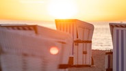 Strandkörbe am Strand bei untergehender Sonne. © Imago Images / Fotostand 