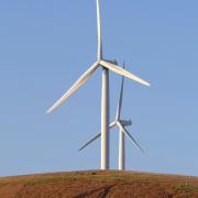 Two wind turbines on a hill. Photo: Unsplash/Rory Tucker