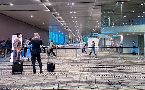 Passengers wearing face masks stand near a terminal gate at Changi International Airport on July 14, 2021 in Singapore, Singapore. Singapore's Changi Airport, one of the world's key transit hubs, has seen passenger numbers plummet as the ongoing Covid-19 pandemic continues to have a severe impact on air travel.