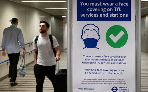 A poster reminds passengers to wear face coverings as they arrive at King's Cross Underground Station on the morning of Freedom Day