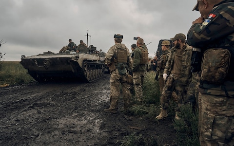 Ukrainian military vehicles move on the road in the freed territory in the Kharkiv region