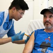 Nurse Christian Medina administers patient Steve Young with his first jab at UCLH.