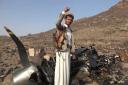 A Houthi fighter celebrates in front of what they said is debris of an American MQ9 aerial vehicle (Houthi Media Office, via AP)