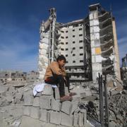 A Palestinian boy sits outside a residential building destroyed in an Israeli strike in Rafah, Gaza Strip