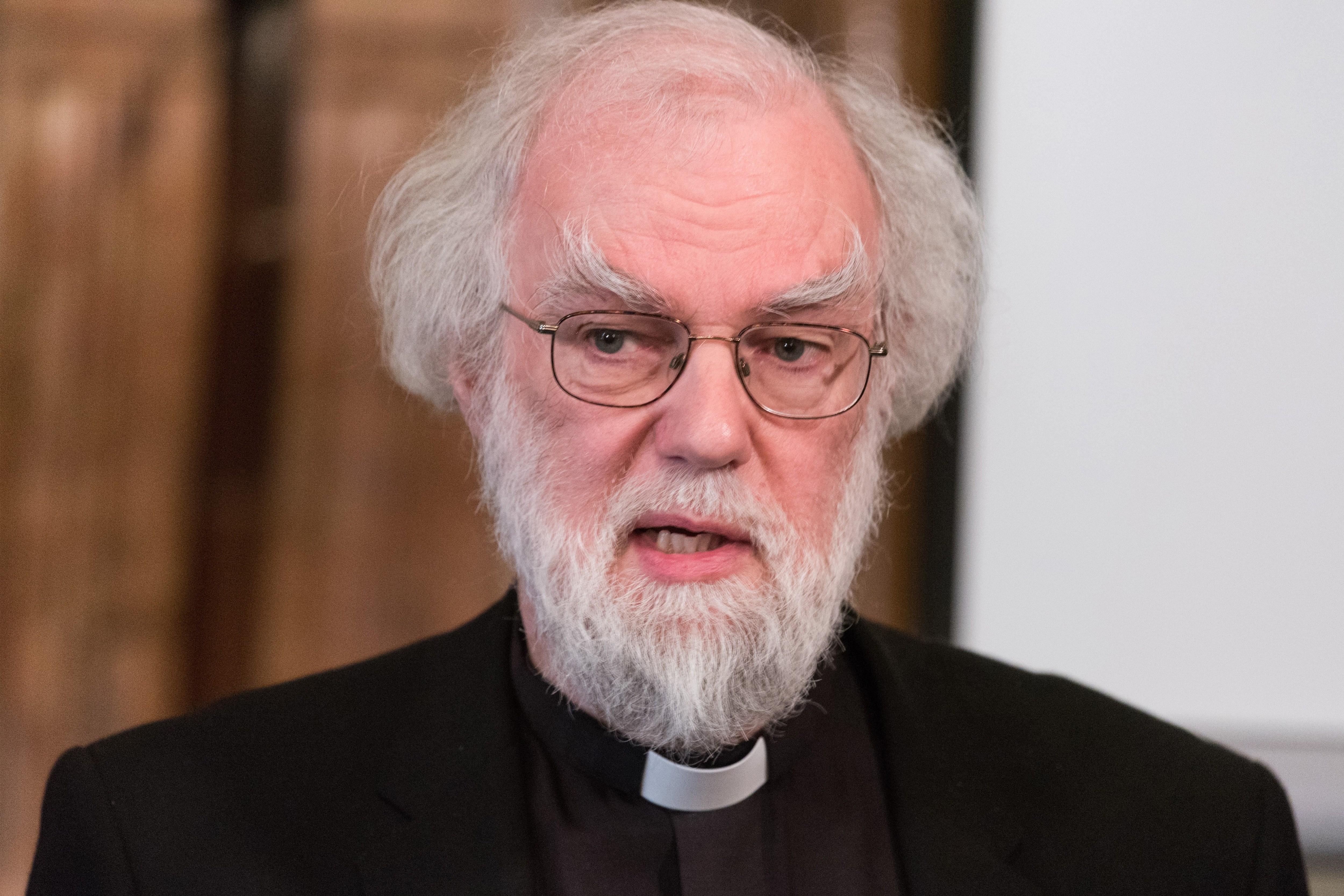a man with glasses and a beard is wearing a clergy collar
