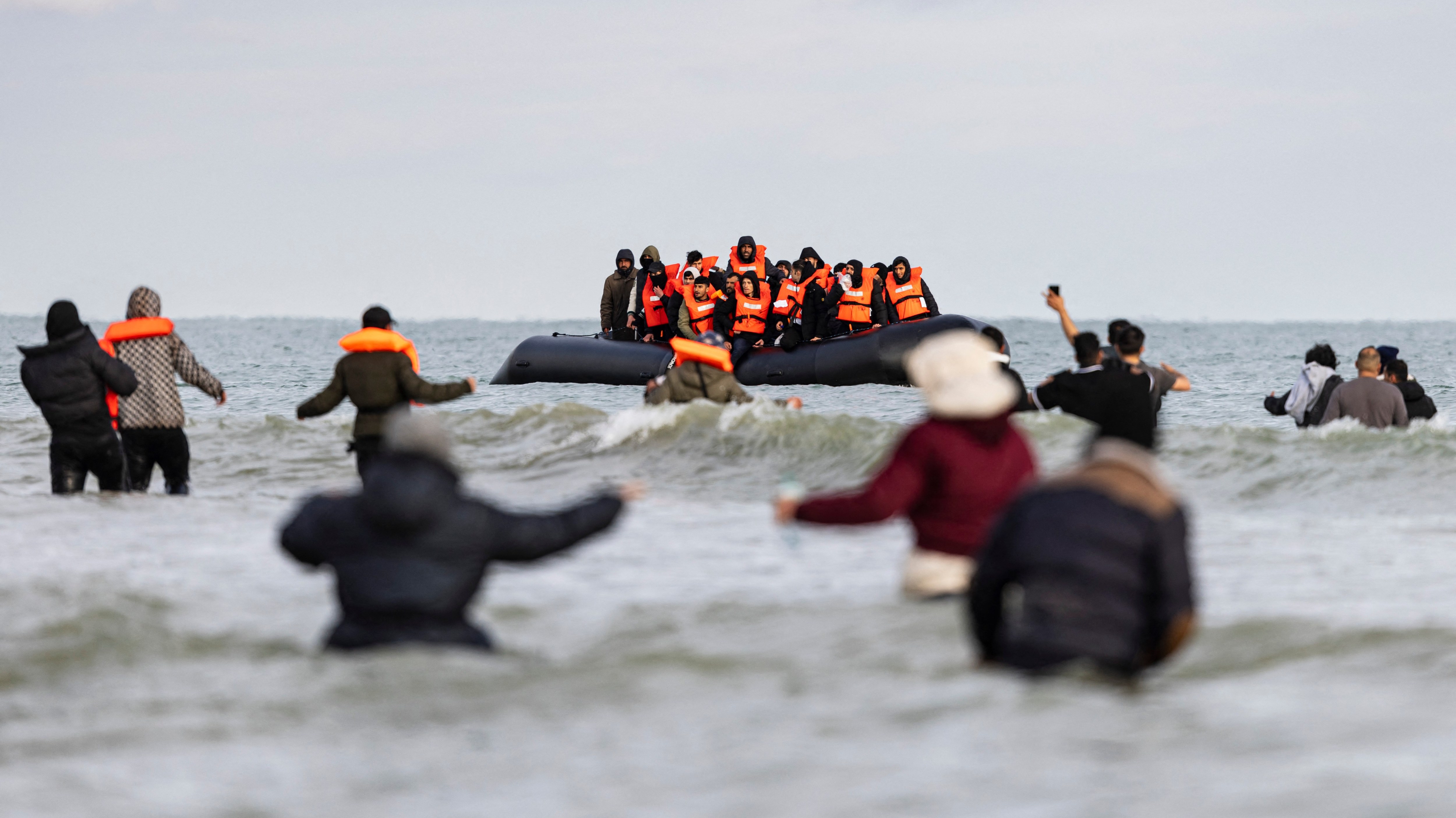 Migrants wade to a smuggler’s boat in an attempt to cross the English Channel on Friday. This is the first year that more than 7,000 people have arrived in small boats by the end of April