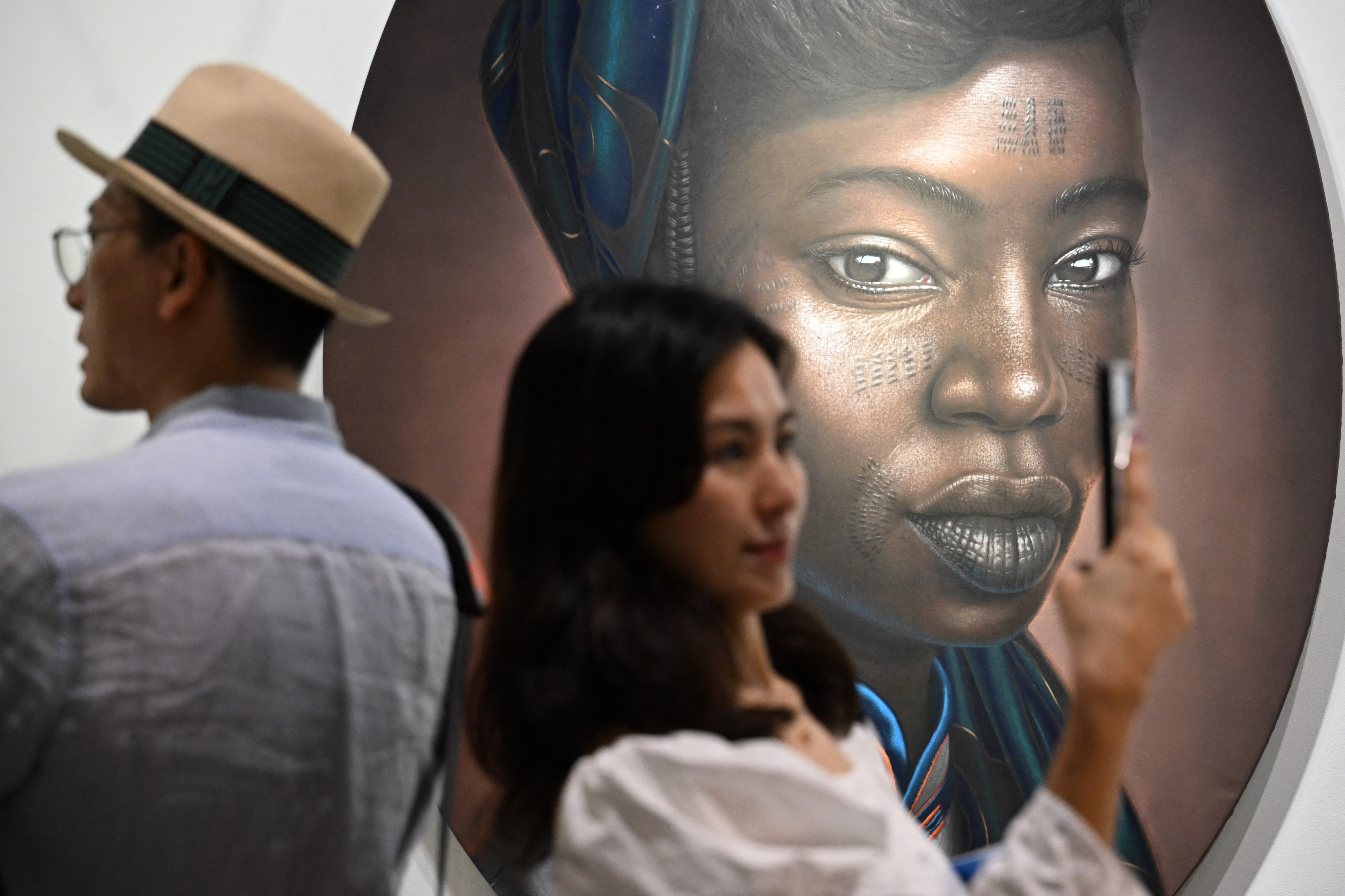 An admirer takes a photograph of works by Nigerian artist Babajide Olatunji at Art Basel in Hong Kong